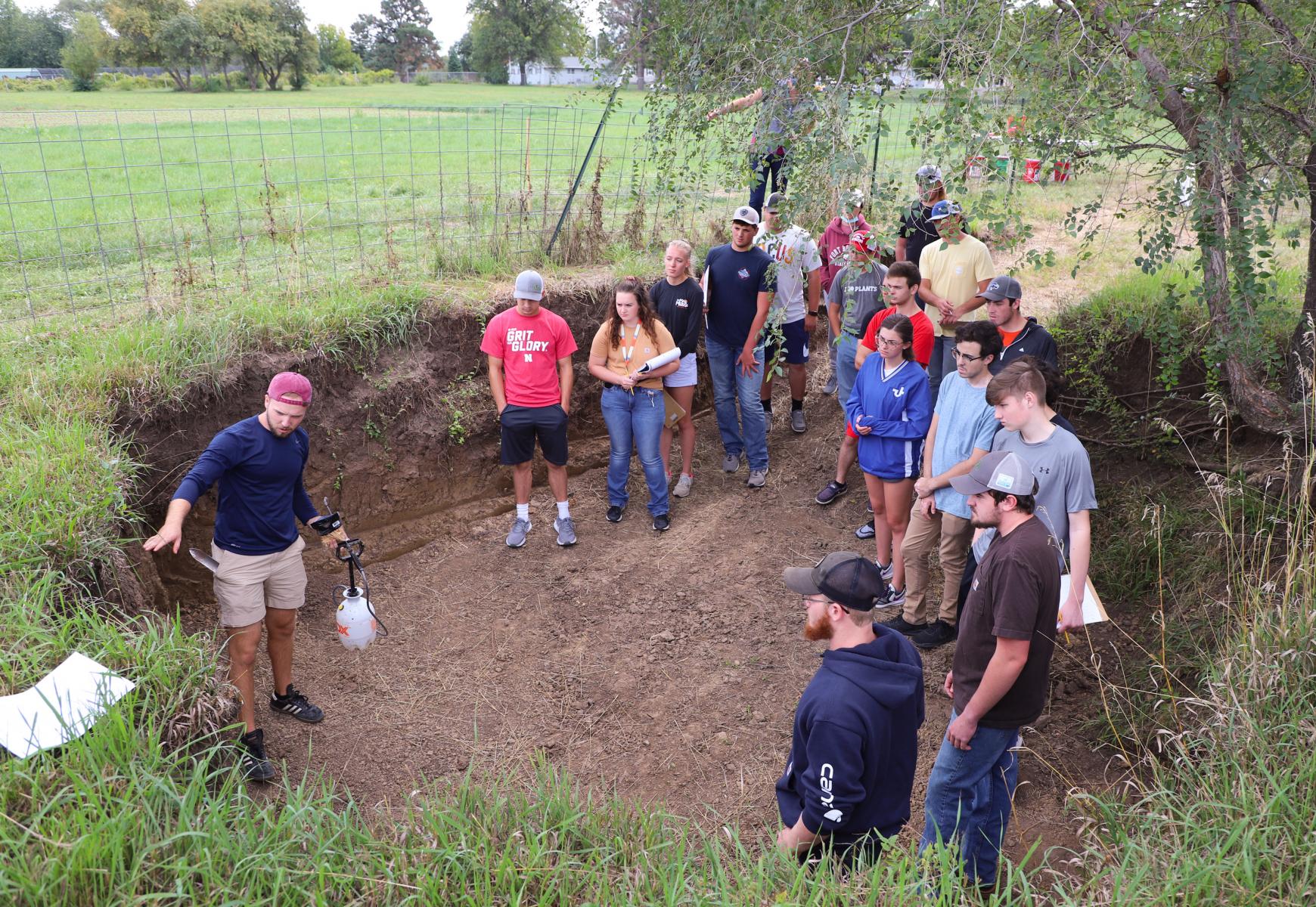 John Tines, sophomore turfgrass and landscape management major and teaching assistant for the Agronomy/Horticulture/Soil 153 Soil Resources lab, gives directions in the East Campus soil pit on how to describe a soil profile and how to identify soil properties in relation to how they affect land use. Meghan Sindelar, Department of Agronomy and Horticulture assistant professor of practice, teaches the course.