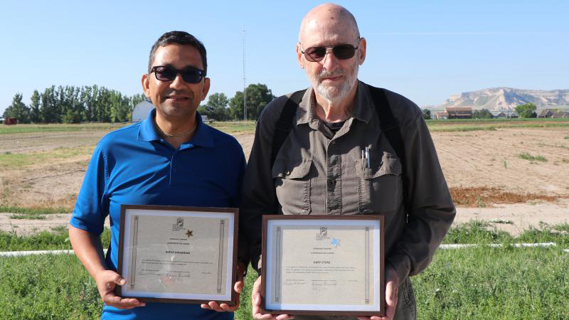 Soil and Water Conservation Society members Bijesh Maharjan (left) and Extension Educator Gary Stone hold their Commendation Awards from the SWCS Nebraska Chapter. | Photo by Chabella Guzman