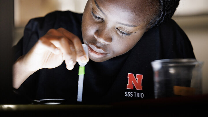 Riada Riyangow uses a pipette while learning about biological sciences research in a Manter Hall lab.