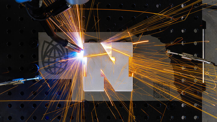 A robotic welder at Nebraska Innovation Studio welds a Nebraska N to a cutout in the shape of Nebraska.