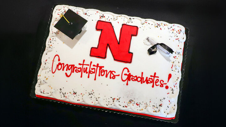 Graduation cake with a red "N," cap, diploma, and "Congratulations Graduates!" written in red.
