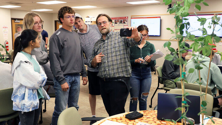 Christian Stephenson, assistant professor of practice in agronomy and horticulture, demonstrates to students in the new Experiments in Plant Science course the use of a Forward Looking Infrared thermographic camera that measures the temperature of a plant. 