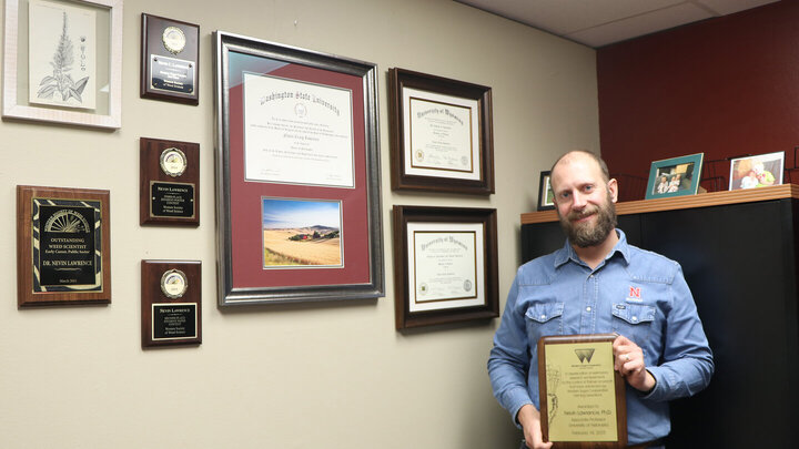 Nevin Lawrence, Nebraska Extension Weed Management Specialist, holds the award he received from Western Sugar.