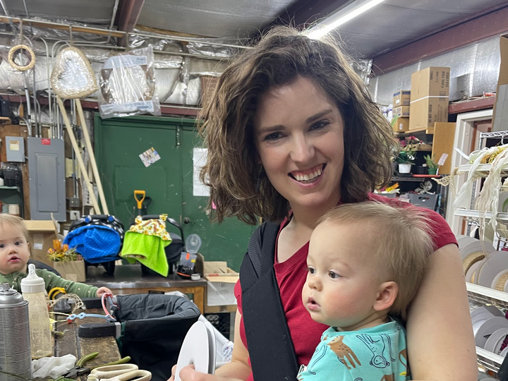 Jaclyn Nelson poses for a photo in her flower shop with her two babies