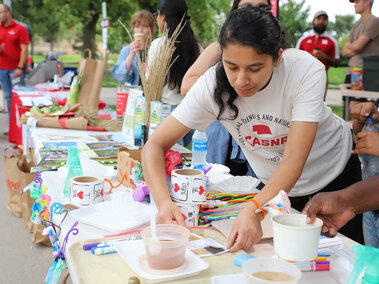 An Agronomy and Horticulture graduate student creates a soil profile using a plastic spoon, water and three different colors of brown powder to show kids what the layers of soil beneath the earth look like at the August 9, 2025 Discovery Days.