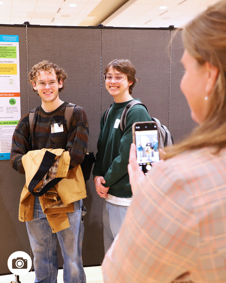 Becky Young, associate professor of practice in agronomy and horticulture, snaps a photo of Jane Jewell (from left), Jacob Vankat and Shawn Hojnacke, undergraduate students in Plant and Landscape Systems/Soil 153 Soil Resources, with their infographic soil poster Dec. 10 in the Nebraska East Union. 