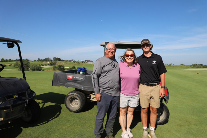 ost Rail Golf Club Assistant Superintendent Steve Merkel (from left) and University of Nebraska–Lincoln Professor of Practice Anne Streich, both Nebraska turfgrass science and management alumni, pose for a photo with Nate Agosta, student intern, at hole 12 overlooking the clubhouse.