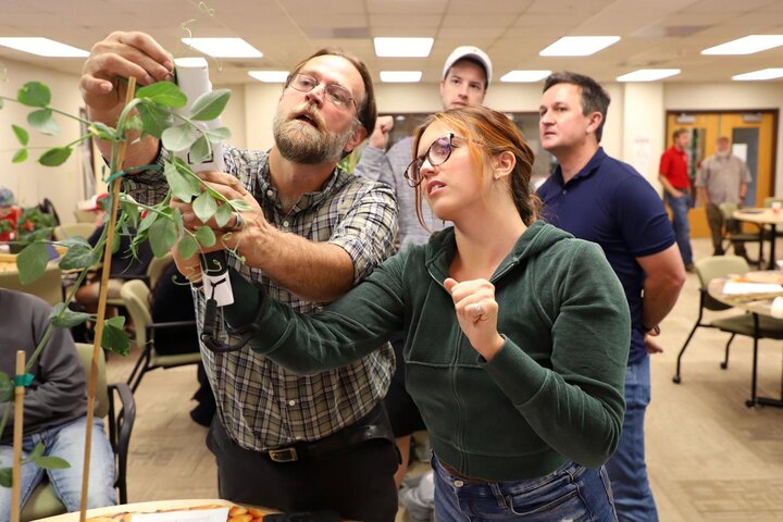 Christian Stephenson, assistant professor of practice in agronomy and horticulture (left), and Ella Jorgensen, a senior plant and landscape systems major, take measurements of stomatal conductance and chlorophyll florescence on a pea plant