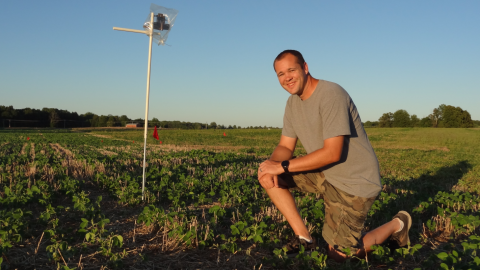 Greg Kruger, weed science extension specialist at the University of Nebraska-Lincoln, kneels in a soybean field that recently received a treatment of dicamba. He continues to conduct research on dicamba drift and boom heights.