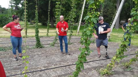 Milos Zaric, a Nebraska doctoral student in agronomy and horticulture (center), presents the 3/4-acre hop yard associated with his work at the West Central Research, Extension and Education Center in North Platte Aug. 21.