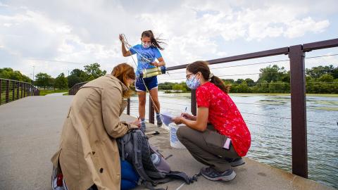 Malayna Wingert, a sophomore biological systems engineering major from Sterling, Nebraska, lifts a water sample out of Holmes Lake as Anni Poetz and Maddie Carpenter record data in August 2020. The students worked under faculty member Jess Corman this summer through Nebraska's UCARE program.